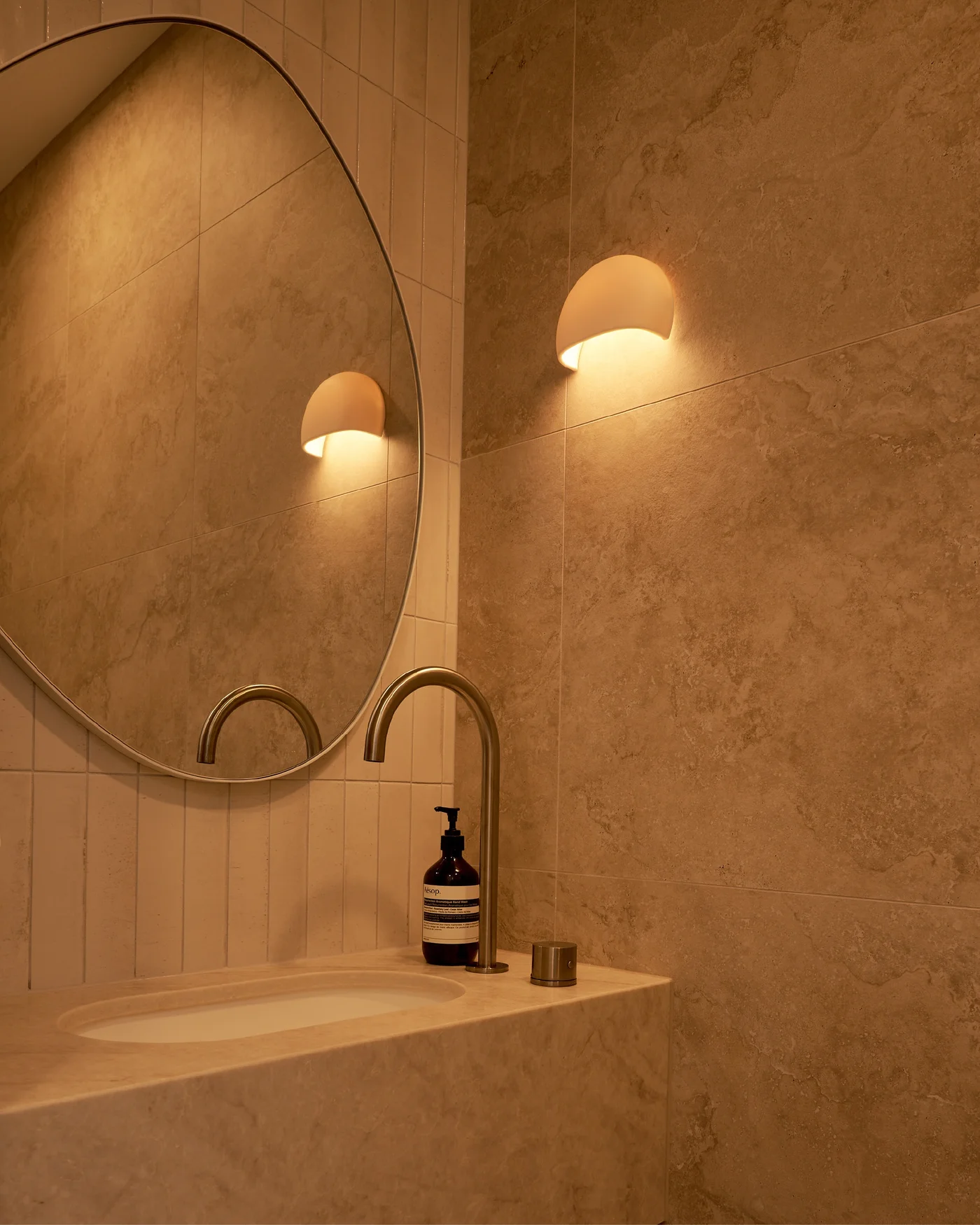 Bathroom vanity with oval mirror and stone surfaces